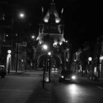 a black and white photo of a city street at night