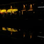 a building lit up at night with lights reflecting in the water