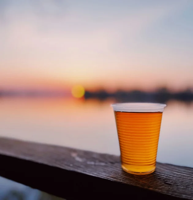 A cup of beer sitting on a wooden ledge