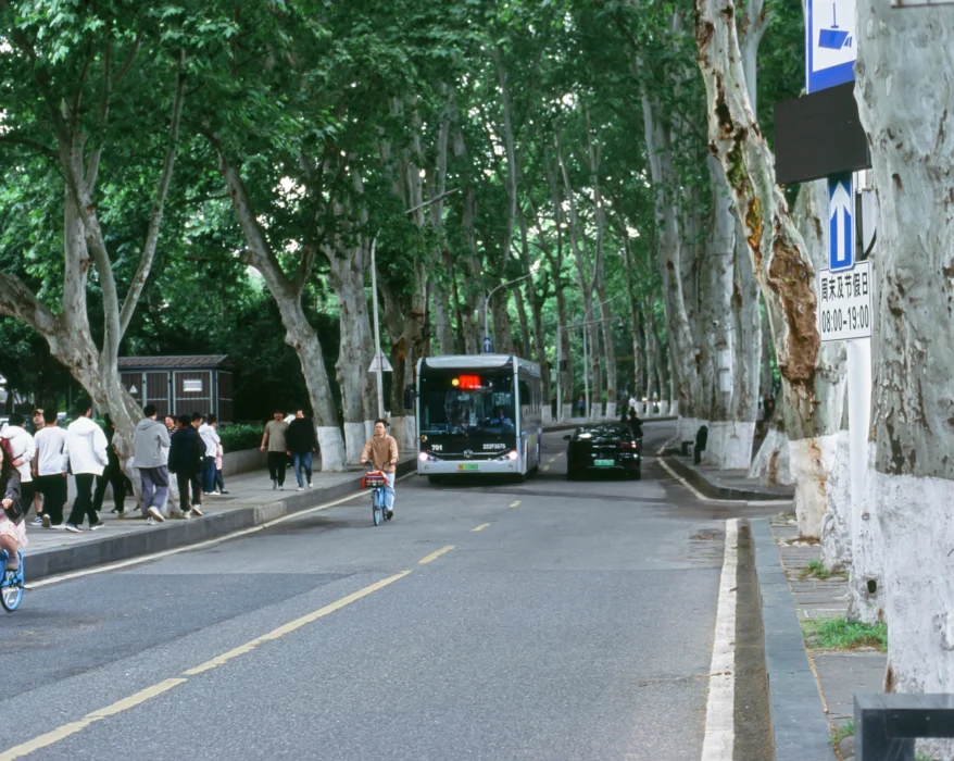 a group of people walking down a street next to a bus