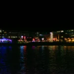 a large body of water at night with buildings in the background