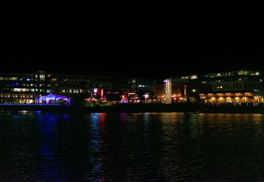 a large body of water at night with buildings in the background