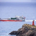 a red and white boat traveling across a body of water