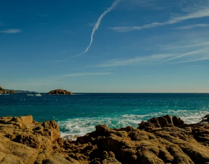 brown rock formation on sea under blue sky during daytime