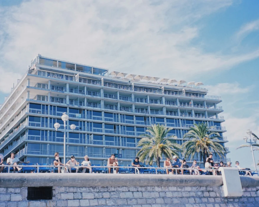 people sitting on concrete bench near white concrete building during daytime