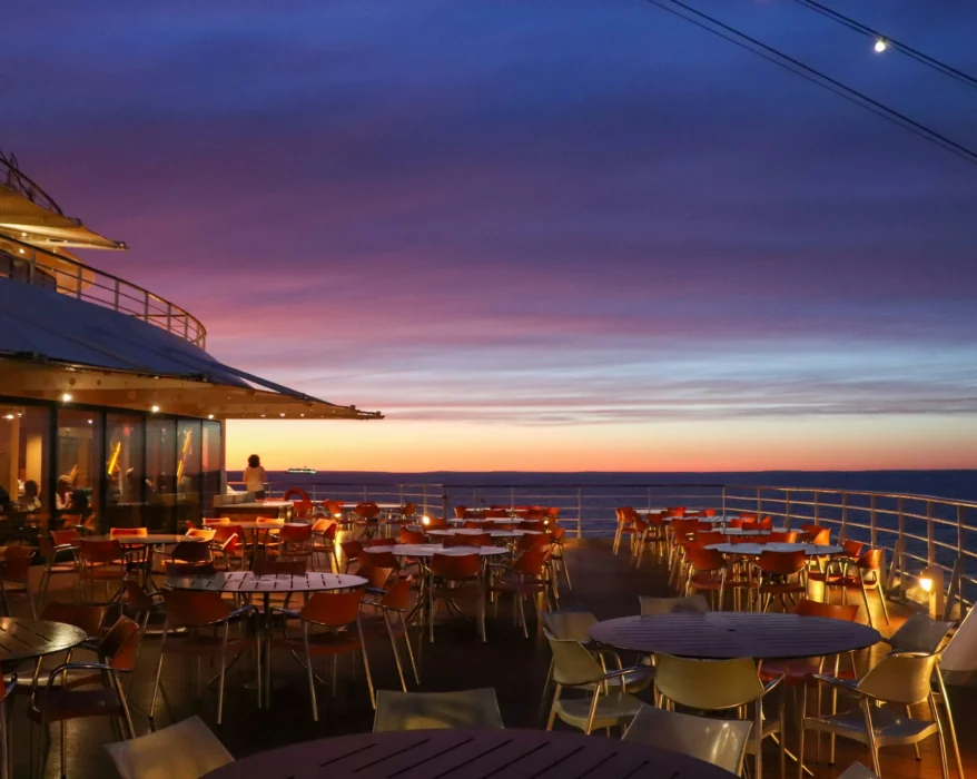 the deck of a cruise ship with tables and chairs