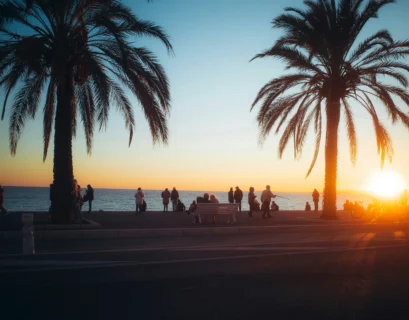 The sun is setting on the beach with palm trees