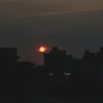 the sun is setting over a city skyline